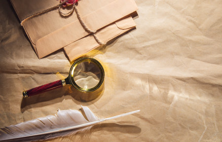 feather and letters and magnifier on vintage paper backgroundの写真素材