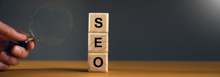 SEO text on wooden cube and hand magnifying glass
