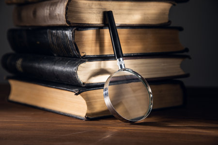 A magnifying glass on a stack of books on wooden tableの写真素材
