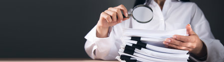 Businesswoman looking through a magnifying glass to documentsの写真素材