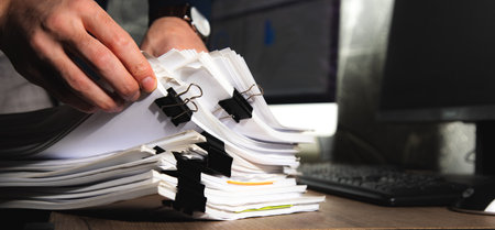 Businessman hands working in stacks documents of paper filesの写真素材