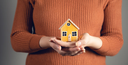 Small home model on woman hand. Family life and business real estate conceptの写真素材