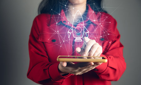 Startup and company growth concept. Woman holding phone and rocket iconの写真素材