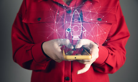 Startup and company growth concept. Woman holding phone and rocket iconの写真素材