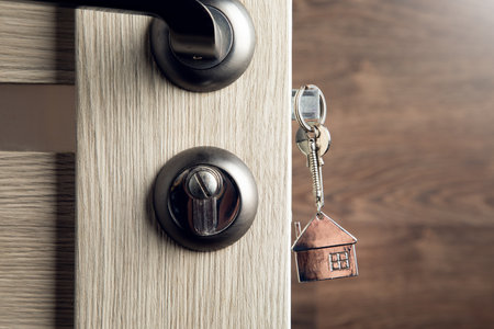 House key on a house shaped silver keyring in the lock of a doorの写真素材