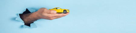 hand of man hold miniature toy cars on the blue background. automobile and transportation conceptの写真素材