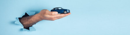 hand of man hold miniature toy cars on the blue background. automobile and transportation conceptの写真素材