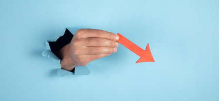 man hand holding falling red chart arrow. Crisis and fall conceptの写真素材