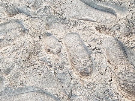 Beach sand in the rays of the summer sun. Sunny day on the shore. The yellow-brown sand is uneven with dents and footprints of people.の写真素材