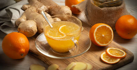 Cup of ginger tea with honey and lemon on wooden table, still life, closeup, vignette, banner, horizontal orientationの写真素材