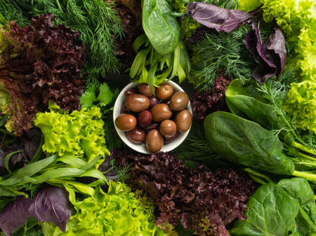 top view - various edible fresh herbs, greens of green and purple are laid out in a circle, in the...