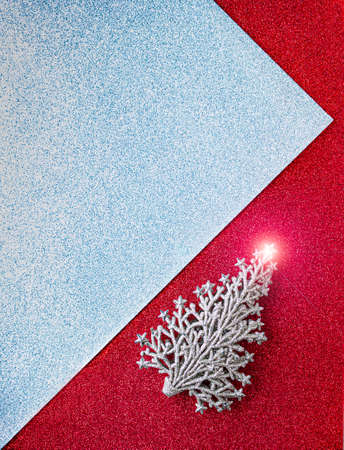 flat lay of paper with red and silver glitter forming an acute angle and decorated with a Christmas golden toy tree with glareの写真素材