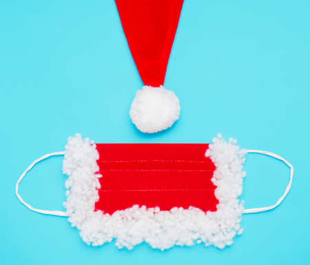 protective mask and part of a hat with a pompom for Santa Claus, red and white, on a blue backgroundの写真素材