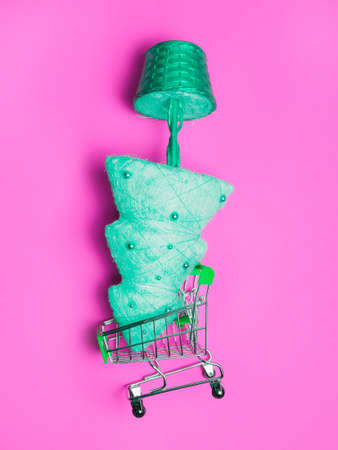 golden christmas tree upside down in a shopping cart, on a pink background, neon toningの写真素材