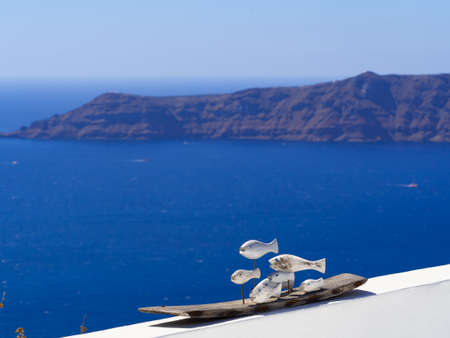 wooden fish are laid out on a stone white fence against a sea landscape Santoriniの写真素材