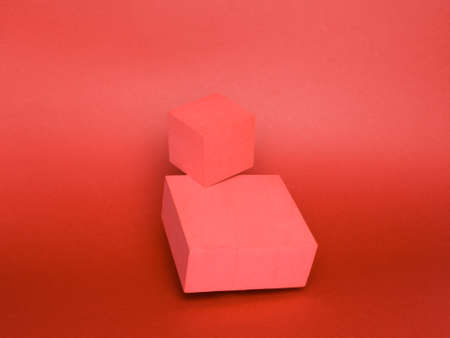 Photo of a bright podium (pedestal) of two cubes on a paper background. In red, with gradient and...