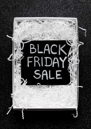 black board with chalk inscription "black friday sale" in a box with white paper shred on a black glitter backgroundの写真素材