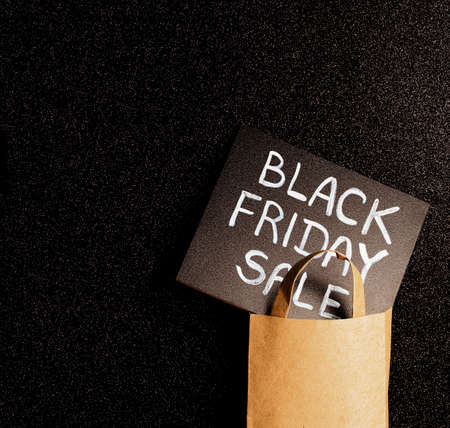 black board with chalk inscription black friday sale in craft package on a black glitter background