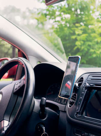 smartphone mounted inside the red car next to the steering wheel for navigation