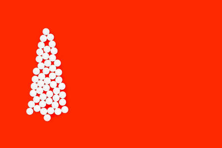 flat lay of christmas tree made of white pills on a red background, copy spaceの写真素材