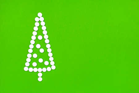 flat lay of christmas tree made of white pills on a green background, copy spaceの写真素材