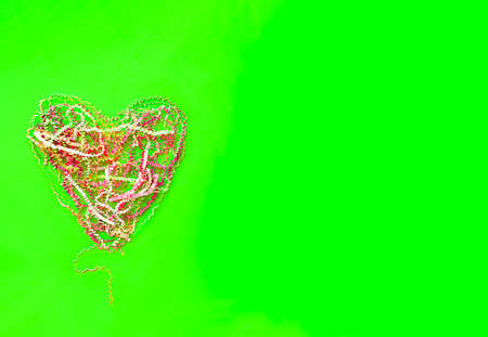 heart folded from pink crimped paper ribbon, on a fluorescent green backgroundの写真素材