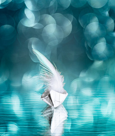 paper boa with a feather instead of a sail in defocused lights and bokehの写真素材