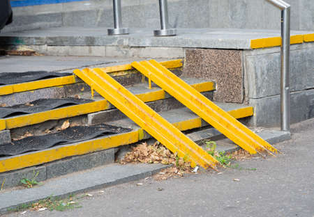 Yellow ramp on the stairs at the entrance of the house for the disabled or a baby carriage.の写真素材