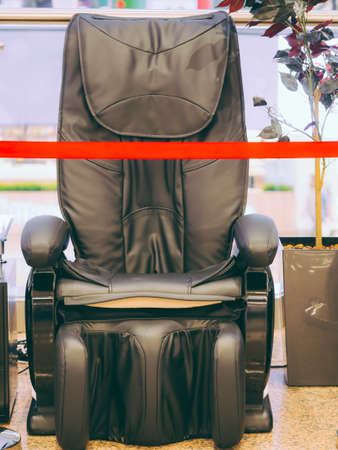Lines of red barrier tape around massage chair in a mall, in a public place.