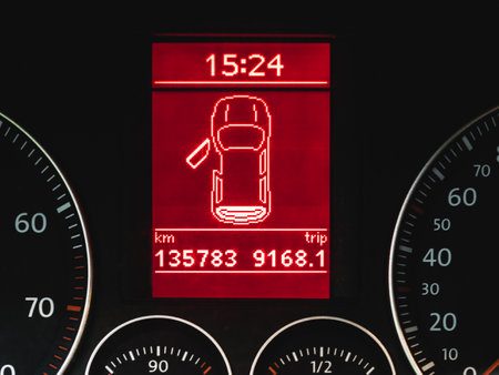 Fragment of a car dashboard. Red display with a silhouette of a car with an open door, showing the...