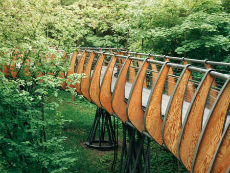 High pedestrian bridge inside the forest for quiet walks at tree level. The bridge is fixed on supports, railings with wooden decor.の写真素材