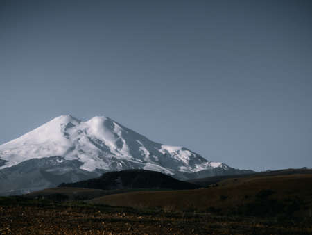 Mount Elbrus, night landscape. View of the highest mountain of the Caucasian ridge - Elbrus. Elbrus with two peaks against the background of a clear sky, the mountain is covered with snow. Copy space.の写真素材