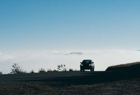 Silhouette of a car on a high mountain road. Road high in the mountains, above the clouds. Copy space.の写真素材