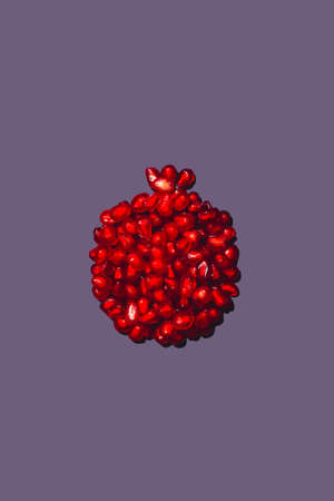 Ripe red pomegranate seeds stacked in the shape of a pomegranate, on a purple background, isolited, Whole fruit shaped pomegranate seeds.の写真素材