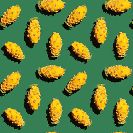Yellow pitahaya, dragon fruit. Shambolic seamless pattern of yellow pitahaya halves on a green background. Tropical patternの写真素材