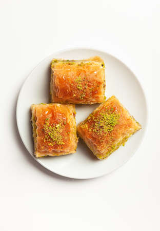 baklava with pistachios, 3 pieces, on a white plate, on a light background, view from aboveの写真素材