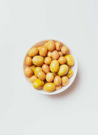 large green olives in a white bowl, on a light background, view from above
