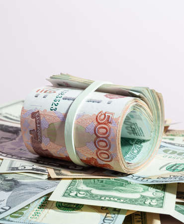 A bundle of Russian paper money in denominations of 1 and 5 thousand rubles, rolled up, lies over USA and European paper money - USD and EURの写真素材