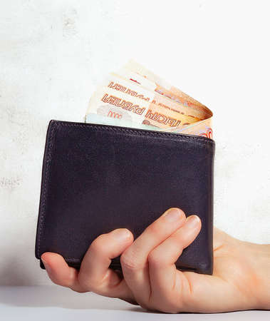 close-up of the purse in the hand, in the purse there is cash Russian money - rubles in denomination...