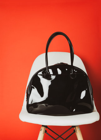 white chair near red wall, black lacquer bag on chair, front view, copy space, mockupの写真素材
