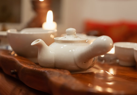 Blurred background - Japanese tea party, close-up of white utensils on a wooden tray, cozy atmosphere by candlelightの写真素材