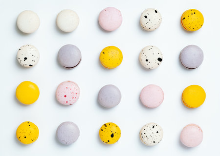 even rows of macarons, multi-colored macaron cookies with specks on a light background, top viewの写真素材