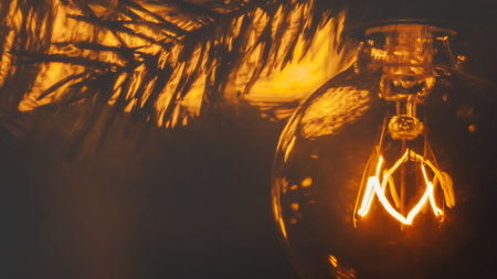 Incandescent bulb of electric garland in retro style, extreme close-up, warm yellow light, Christmas atmosphereの写真素材