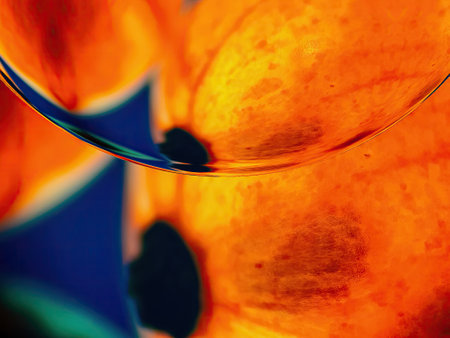 A vibrant, abstract image featuring a curved, glossy surface in shades of orange and yellow. The surface reflects blue and green hues, creating a sense of depth and dimensionの写真素材