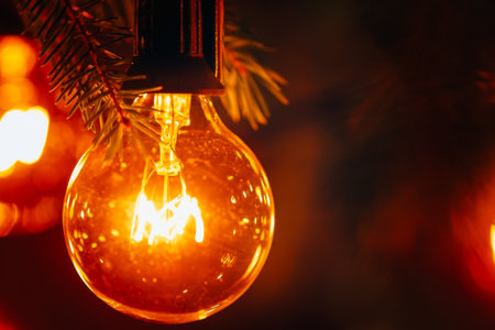 Incandescent bulb of electric garland in retro style, extreme close-up, warm yellow light, Christmas atmosphereの写真素材