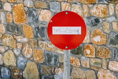 Red circular traffic - stop sign, with handwritten inscription "Welcome" on itの写真素材