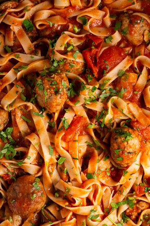 Texture of pasta in tomato sauce with meatballs as a background. A close shot of pasta with tomato sauce. macro photo. Tagliatelle pasta with tomato sauce and meatballs.の写真素材
