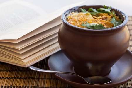 Roast with meat, potatoes in a clay pot on a napkin with book