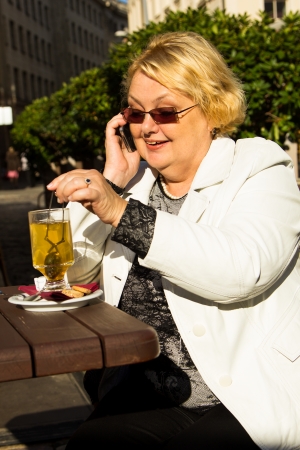 Happy senior woman talking on the phone during coffee breakの写真素材