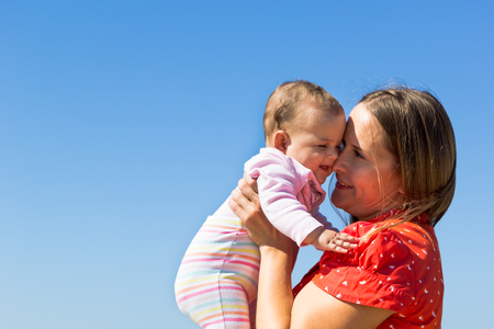 Mother playing with cute little daughter on the beachの写真素材